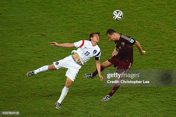 Koo Ja-Cheol of South Korea and Sergey Ignashevich of Russia go up for a header during the 2014 FIFA World Cup Brazil Group H match between Russia...