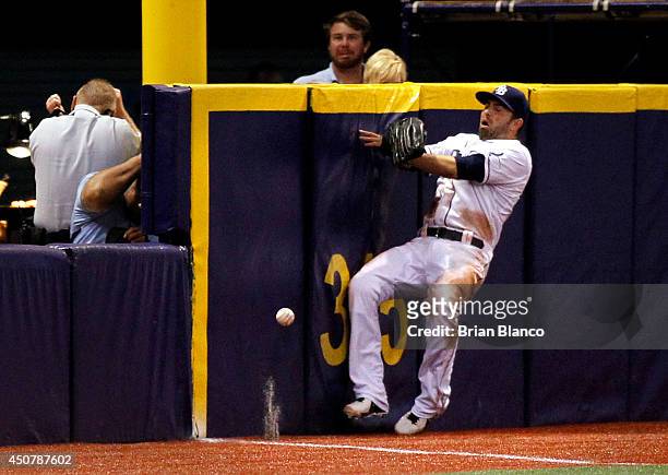 Left fielder David DeJesus of the Tampa Bay Rays hits the outfield wall attempting to catch a ball that went for a grand-slam home run by Chris Davis...