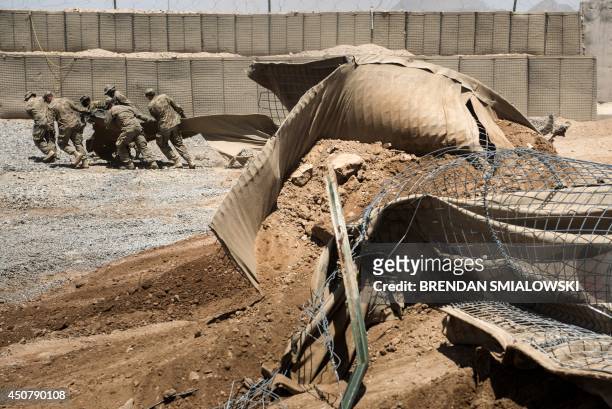 Afghanistan-election-US-unrest,FOCUS by Dan De Luce This photo taken on June 2, 2014 shows US soldiers dragging part of a Hesco barrier after...