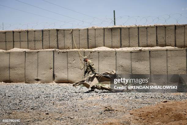 Afghanistan-election-US-unrest,FOCUS by Dan De Luce This photo taken on June 2, 2014 shows a US soldier draggng part of a Hesco barrier after...