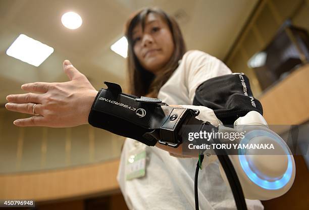An official of Kawasaki City demonstrates a new powered exoskeleton to assist movement of an arm developed by Japan's robot suit venture Cyberdyne...
