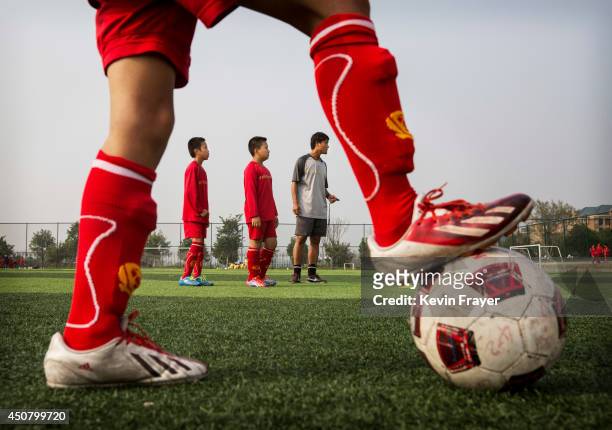 Chinese coach interacts students during training on the at the Evergrande International Football School on June 14, 2014 near Qingyuan in Guangdong...