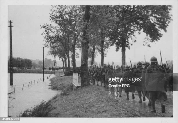 Troops marching towards the front lines, past flooded villages, during World War Two, France, circa 1939-1945.