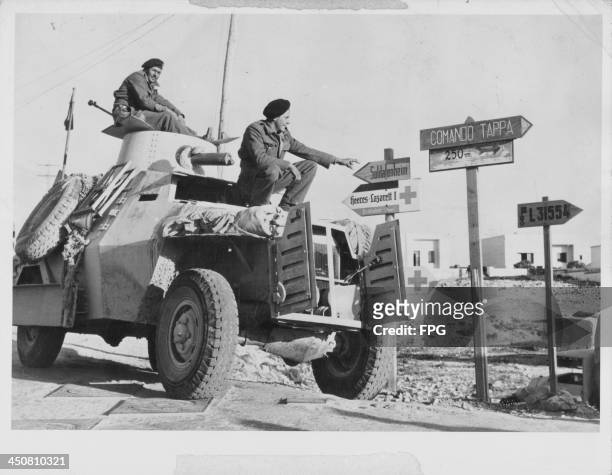 Allied troops in an armored car, attempting to read German and Italian road signs in Derna, on the African Front during World War Two, Libya,...