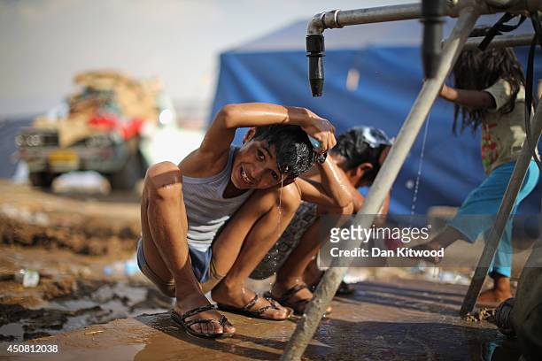 Children wash at a well at a temporary displacement camp on June 13, 2014 in Kalak, Iraq. Thousands of people have fled Iraq's second city of Mosul...