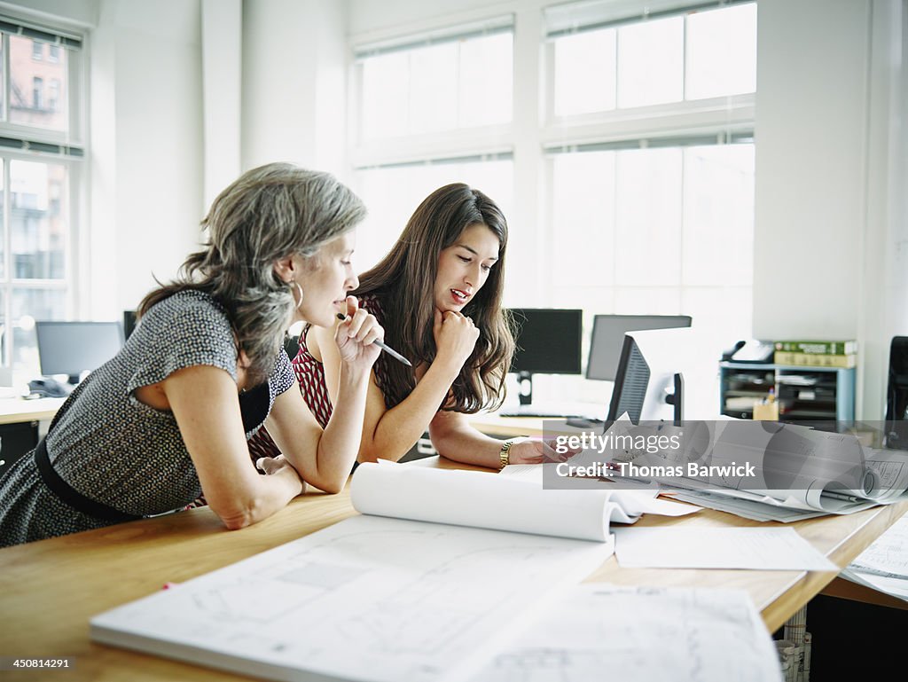 Businesswomen leaning on table discussing plans