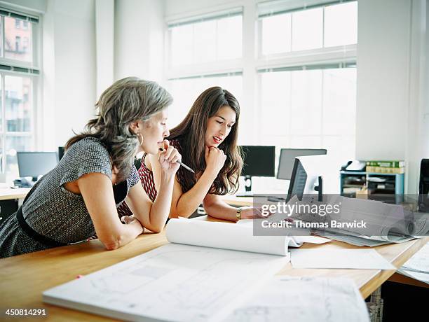 businesswomen leaning on table discussing plans - plan document - fotografias e filmes do acervo