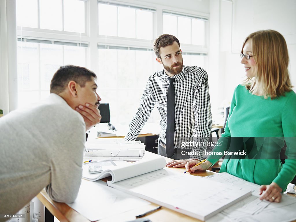 Coworkers discussing plans at table in office