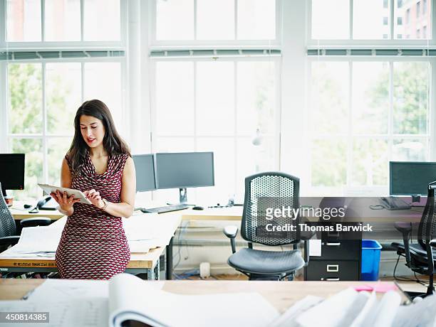 smiling businesswoman working on digital tablet - leanincollection working women stockfoto's en -beelden