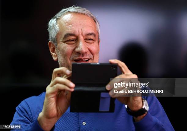 Iran's Head of Football Federation, Ali Kafashian, takes a picture with his mobile phone during a press conference after Iran's training session at...