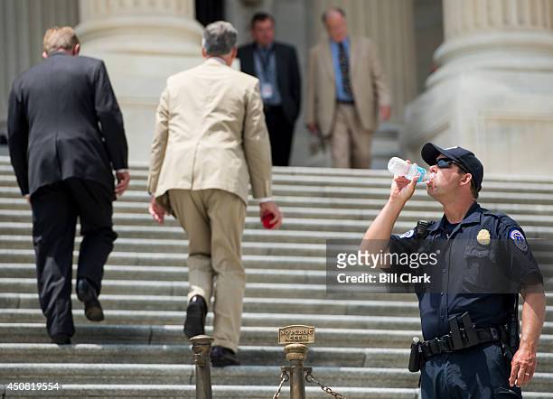 Capitol Police officer stays hydrated as members of Congress walk up the House steps for votes on Wednesday, June 18, 2014. Temperature in the...