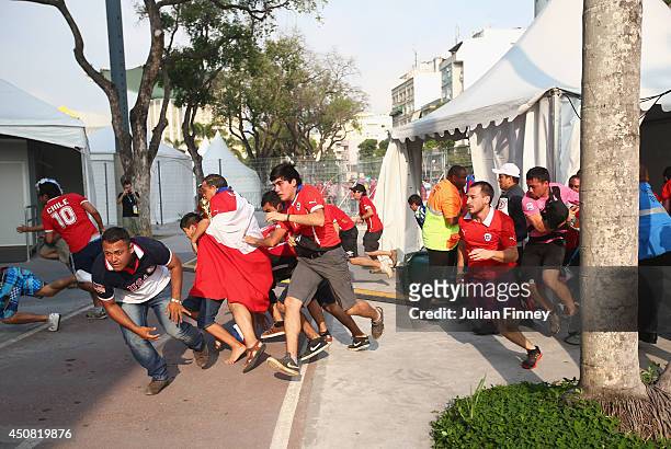 Security personnel attempt to control Chilean fans breaking through a gate outside the stadium prior to the kickoff of the 2014 FIFA World Cup Brazil...