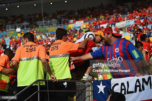 Security personnel try to control Chilean fans on the field of play entering the stands prior to the kickoff of the 2014 FIFA World Cup Brazil Group...