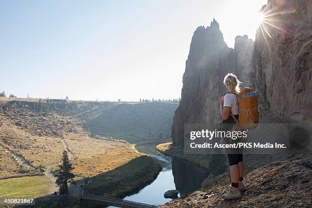 hiker looks out across mtn, river scene, from rock - smith rock state park stockfoto's en -beelden