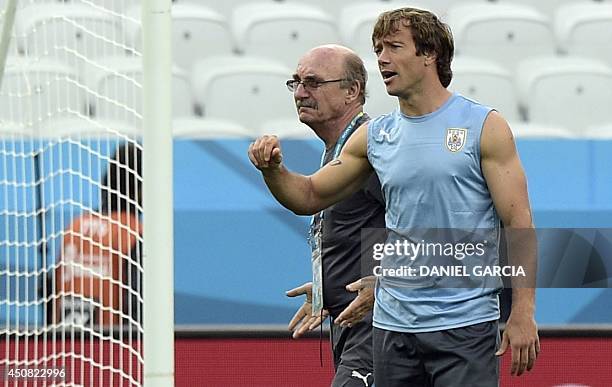 Uruguay's injured defender Diego Lugano walks next to medical doctor Alberto Pan during a training session at Corinthians Arena in Sao Paulo on June...