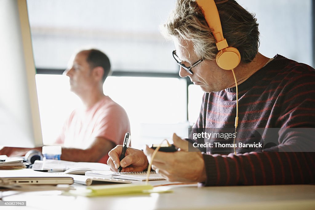 Businessman at desk writing in notepad