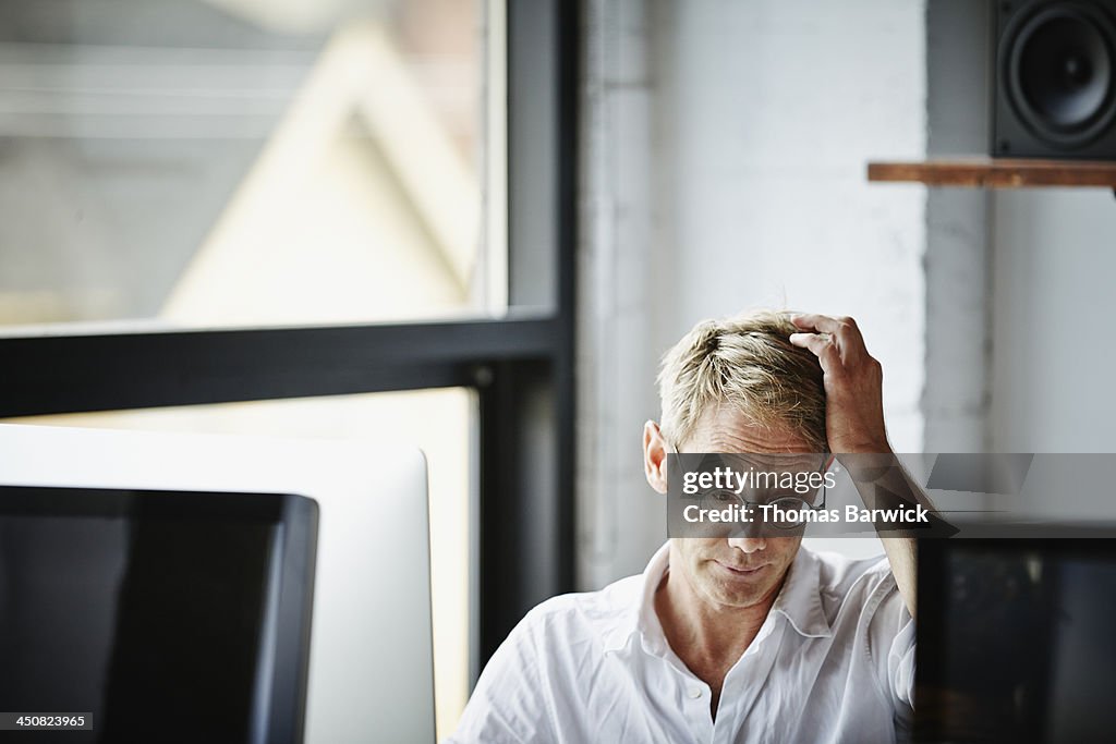 Businessman with hand on head working on computer