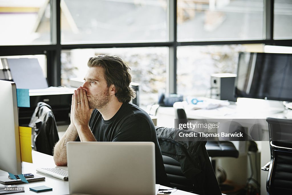 Businessman with hands on chin at workstation