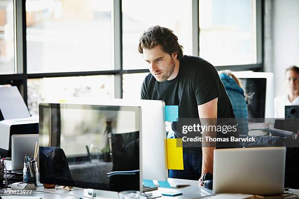 businessman leaning on desk working on computer - sticky-notes-covering-computer-monitor stock pictures, royalty-free photos & images