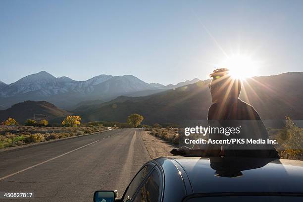 man looks out across desert highway from sunroof - carretera principal fotografías e imágenes de stock