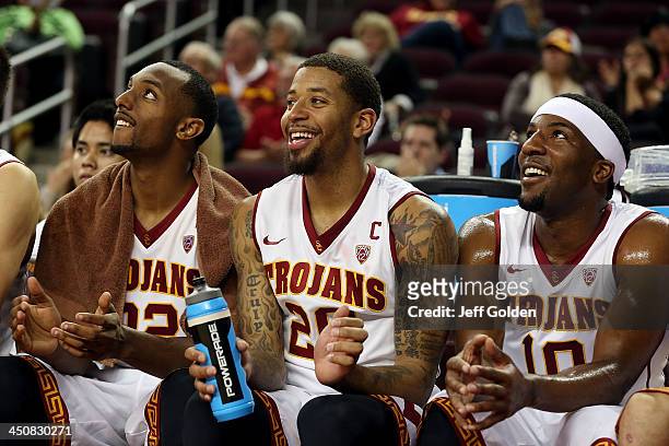 Byron Wesley, J.T. Terrell and Pe'Shon Howard of the USC Trojans smile and applaud from the bench as they watch the videoboard against the Cal State...