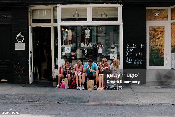 Family sits on a bench while eating outside of a restaurant in the SoHo neighborhood of New York, U.S., on Wednesday, June 18, 2014. The Bloomberg...