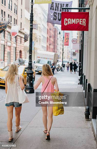 Pedestrians carry shopping bags while walking past the Camper store in the SoHo neighborhood of New York, U.S., on Wednesday, June 18, 2014. The...