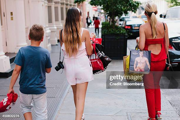 Pedestrians carry shopping bags while walking in the SoHo neighborhood of New York, U.S., on Wednesday, June 18, 2014. The Bloomberg Consumer Comfort...