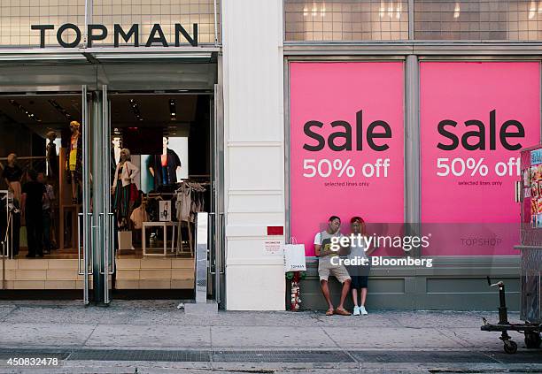 Pedestrians check their mobile phones while standing outside of the Top Man Ltd. Store in the SoHo neighborhood of New York, U.S., on Wednesday, June...
