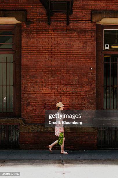 Woman carries a shopping bag while walking in the SoHo neighborhood of New York, U.S., on Wednesday, June 18, 2014. The Bloomberg Consumer Comfort...