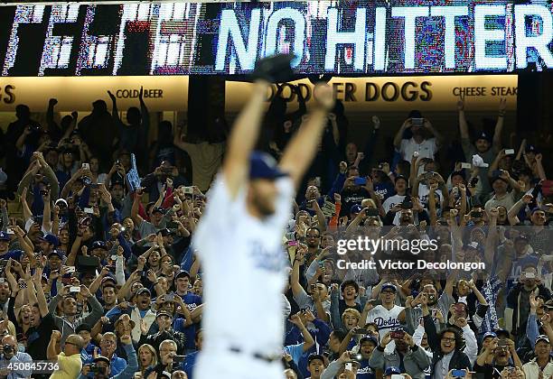 Pitcher Clayton Kershaw of the Los Angeles Dodgers reacts after pitching a no-hitter against the Colorado Rockies as fans jubilate in the background...