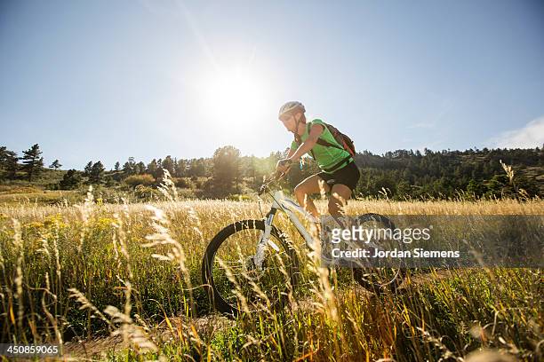 woman biking on a dirt path. - woman on bicycle stock pictures, royalty-free photos & images