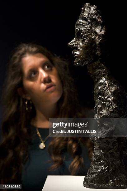 An employee of Christie's auction house poses with a sculpture entitled "Annette IV", conceived in 1962, by Swiss artist Alberto Giacometti, with an...