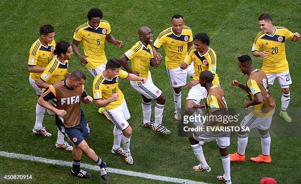 Colombia's players dance after scoring a goal during the Group C football match between Colombia and Ivory Coast at the Mane Garrincha National...