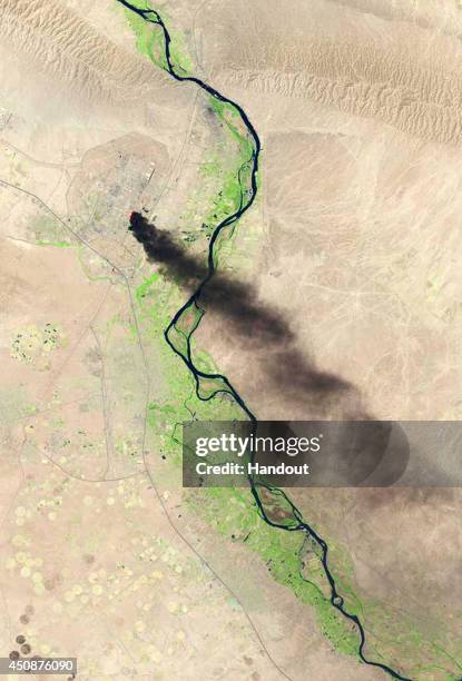 In this handout photo provided by the USGS, A satellite view shows smoke billowing from the Baiji North refinery complex on June 18, 2014 in Baiji,...