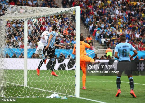 Wayne Rooney of England hits the crossbar with a header against Martin Caceres and goalkeeper Fernando Muslera of Uruguay during the 2014 FIFA World...