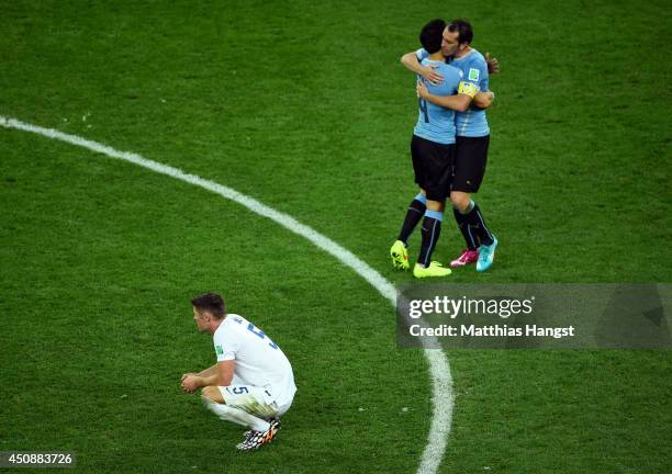 Jorge Fucile and Diego Godin of Uruguay hug as a dejected Gary Cahill of England looks on during the 2014 FIFA World Cup Brazil Group D match between...