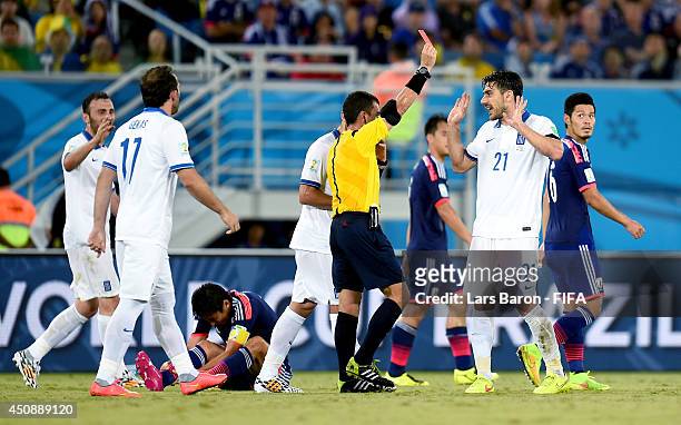 Konstantinos Katsouranis of Greece receives a red card by referee Joel Aguilar during the 2014 FIFA World Cup Brazil Group C match between Japan and...
