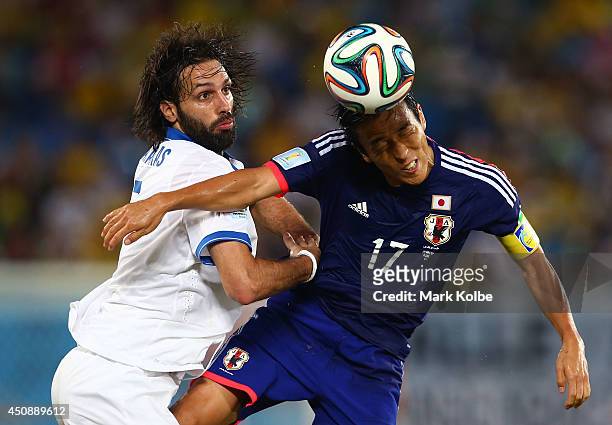 Makoto Hasebe of Japan goes for a header against Giorgos Samaras of Greece during the 2014 FIFA World Cup Brazil Group C match between Japan and...