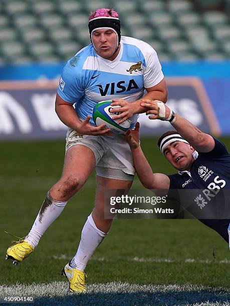 Facundo Gigena of Argentina beats the tackle of James Malcolm of Scotland during the 2014 Junior World Championship match between Argentina and...