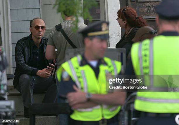 In the role of Whitey Bulger a Johnny Depp film double sits on steps during filming. Filming of the "Black Mass" movie disrupts streets on East...