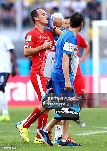 Steve von Bergen of Switzerland is assisted off the pitch after a collision during the 2014 FIFA World Cup Brazil Group E match between Switzerland...
