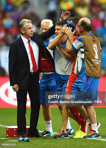 Head coach Ottmar Hitzfeld of Switzerland consoles injured Steve von Bergen after a collision during the 2014 FIFA World Cup Brazil Group E match...