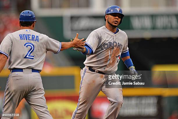 Edwin Encarnacion of the Toronto Blue Jays is congratulated as he rounds third base by third base coach Luis Rivera of the Toronto Blue Jays after...