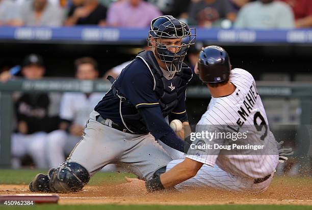 LeMahieu of the Colorado Rockies slides home to score on a single by Corey Dickerson of the Colorado Rockies as catcher Jonathan Lucroy of the...