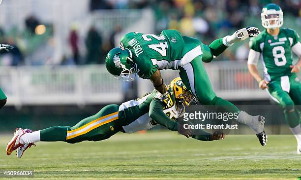 Keith Toston of the Saskatchewan Roughriders is sent into the air by a tackle from Eddie Steele of the Edmonton Eskimos during a pre-season game...