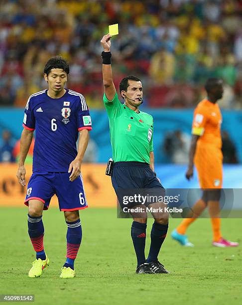 Masato Morishige of Japan receives an yellow card by referee Enrique Osses during the 2014 FIFA World Cup Brazil Group C match between the Ivory...