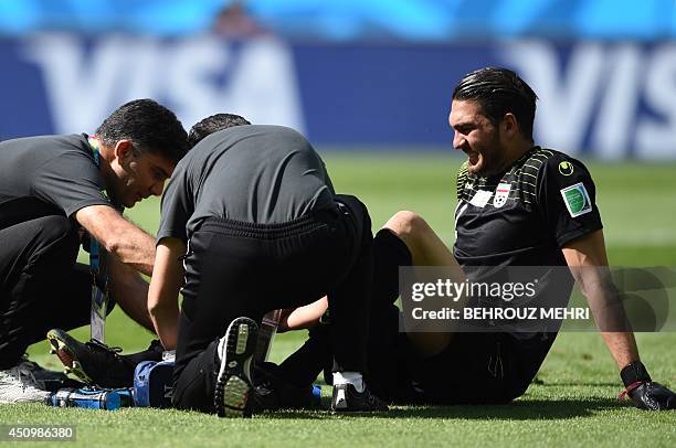 Iran's goalkeeper Alireza Haqiqi is treated for an injury during the Group F football match between Argentina and Iran at the Mineirao Stadium in...