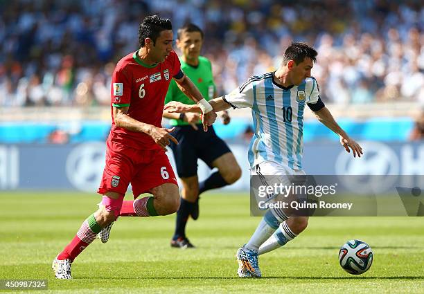 Lionel Messi of Argentina driblles past Javad Nekounam of Iran during the 2014 FIFA World Cup Brazil Group F match between Argentina and Iran at...