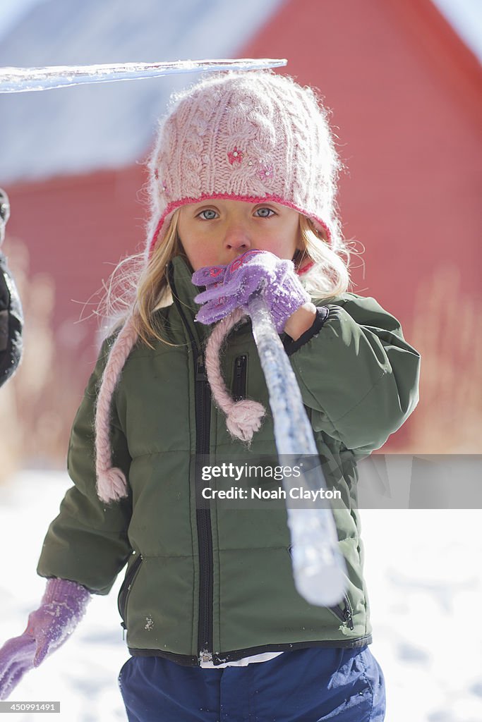 Girl tastes ice cycle in winter